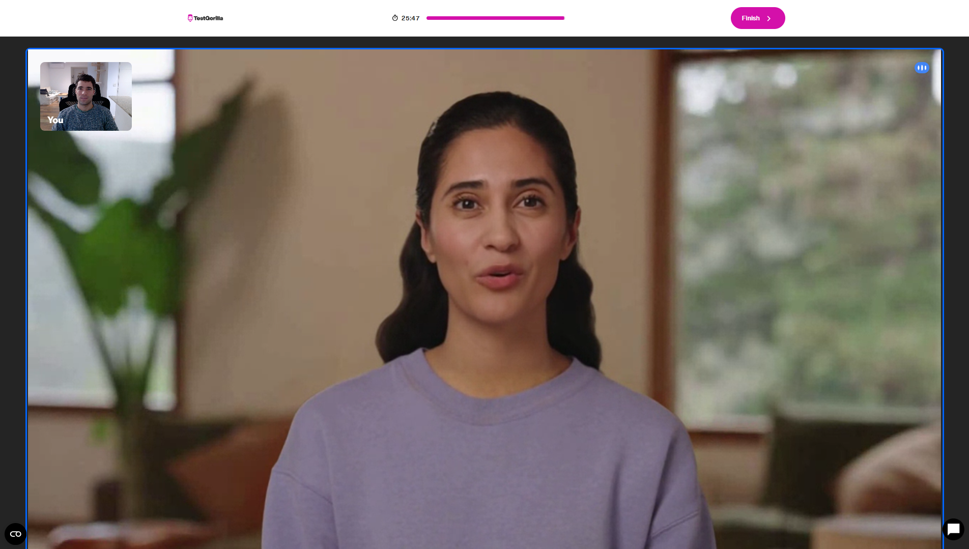 Candidate view of a persona-format AI interview showing the humanoid AI on screen and the candidate's own video preview.